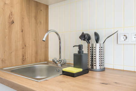 Soap and shampoo dispensers near Ceramic Water tap sink with faucet in expensive kitchen