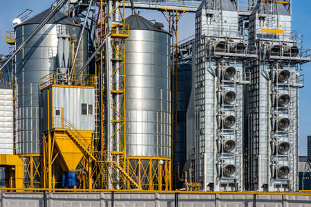 agro silos granary elevator in winter day in snowy field. Silos on agro-processing manufacturing plant for processing drying cleaning and storage of agricultural products, flour, cereals and grain.の写真素材