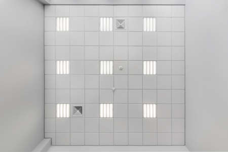 cassette suspended ceiling with square halogen spots lamps and drywall construction in empty room in apartment or house. Stretch ceiling white and complex shape. Looking up viewの写真素材