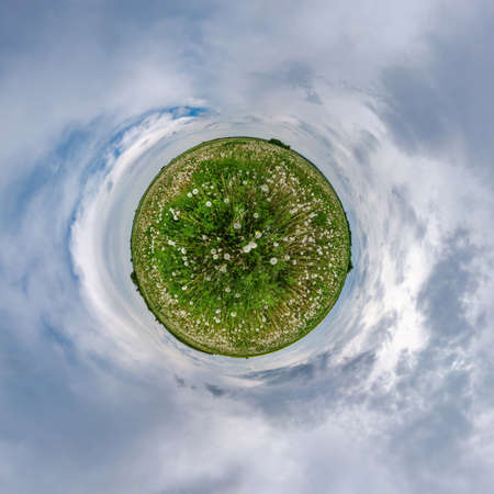 Little planet transformation in dandelions field of spherical panorama 360 degrees in spherical abstract aerial view with awesome beautiful clouds. Curvature of space.の写真素材