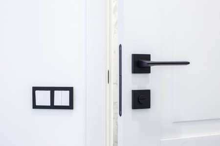 Modern black door handle on white wooden door in interior. Knob close-up elements. Door handle, fittings for interior designの写真素材