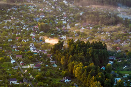 aerial panoramic view of green village with homestads, houses, barns and gravel road in forest