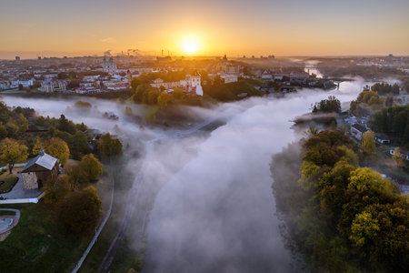 earlier foggy morning and aerial panoramic view on medieval castle and promenade overlooking the old city and historic buildings near wide riverの写真素材