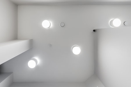 suspended ceiling with halogen spots lamps and drywall construction in empty room in apartment or house. Stretch ceiling white and complex shape.の写真素材