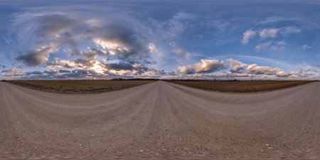 evening 360 hdri panorama on gravel road with clouds on blue sky before sunset in equirectangular...