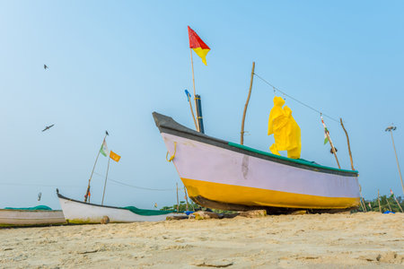 old fishing boats in the sand on the ocean in India on blue sky backgroundの写真素材