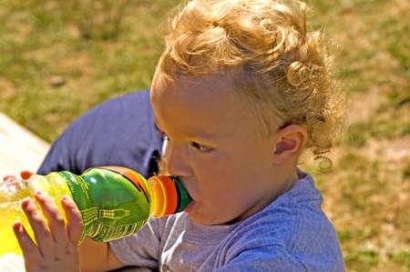 Young boy taking cool drink in hot summer sunの写真素材