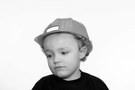 Black and white photography of young boy wearing construction hat looking downの写真素材
