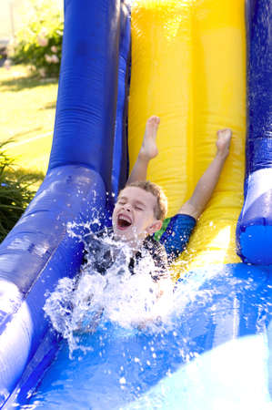 Young boy splashing water at bottom of water slideの写真素材