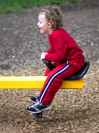 Young boy riding on see-saw outdoors at playground