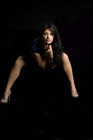 Beautiful model bent over against black backgroundの写真素材