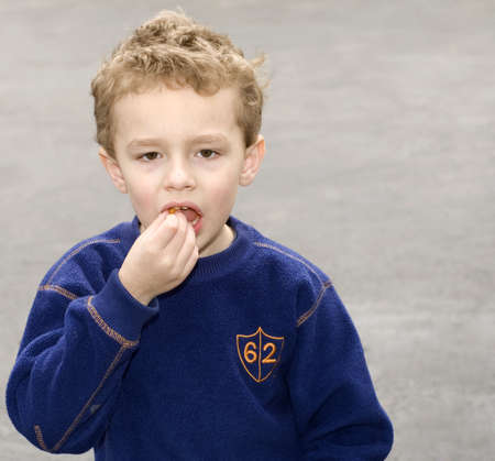 Young boy eating snack with open mouthの写真素材