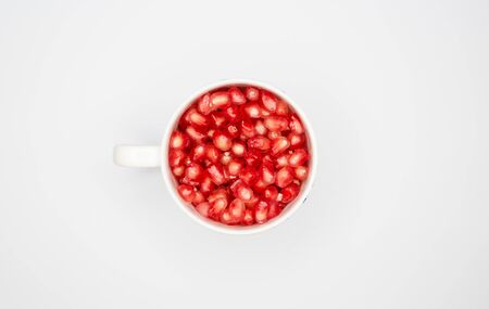 Red pomegranates in cup on white backgroundの写真素材