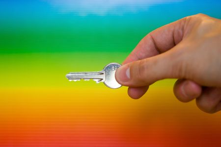 Hand holding a key with a rainbow backgroundの写真素材
