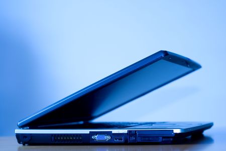 A laptop halfway close with a blue background