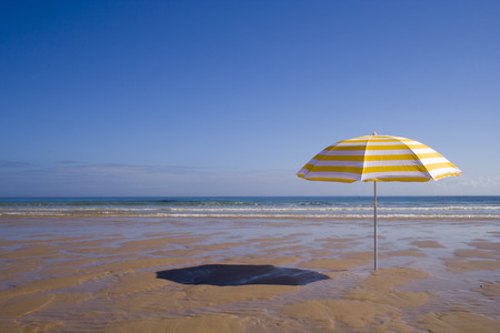 a summer scenic with a yellow umbrella at the beachの写真素材