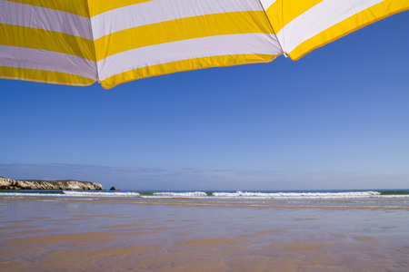 a summer scenic with a yellow umbrella at the beachの写真素材