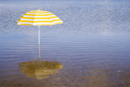 a summer scenic with a yellow umbrella at the beachの写真素材