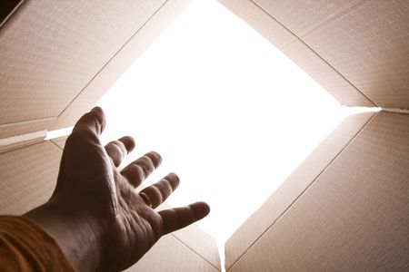 inside view of cardboard box with a hand trying escape (selective focus)の写真素材
