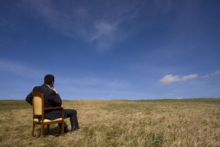 businessman sitting in a chair in outdoor looking to the fieldの写真素材