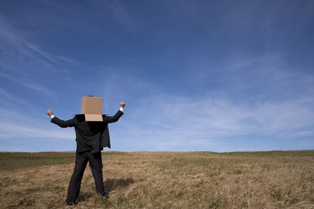 businessman with an box on his head at the fieldの写真素材