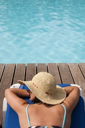 woman with a hat relaxing at the pool