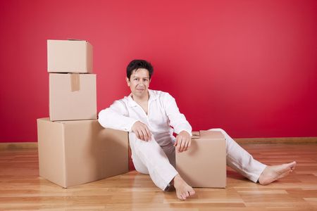 Young men resting next to cardboard boxes after moving houseの写真素材