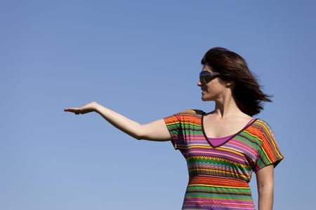 woman with her arm raised showing something up to the skyの写真素材
