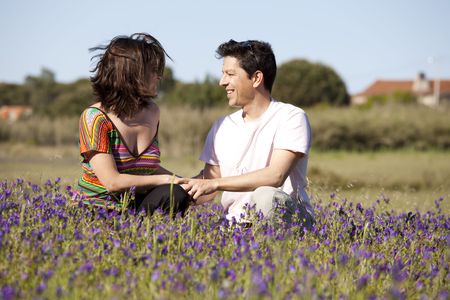 young couple hug in a field with beautiful flowersの写真素材