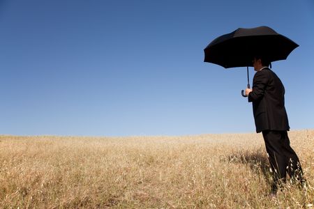 Businessman finding protection outside in the fieldの写真素材