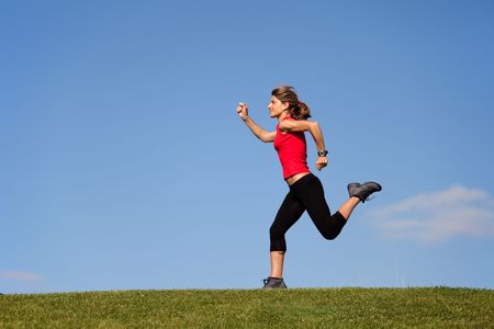young woman running at the top of a hillの写真素材