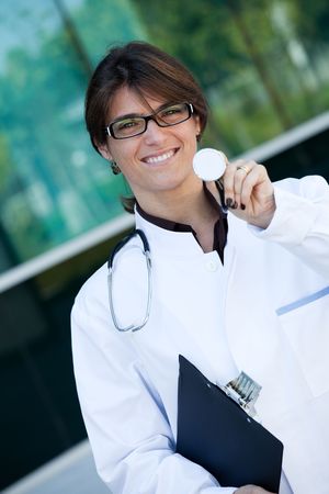 Friendly female doctor smiling to you nest to a clinicの写真素材