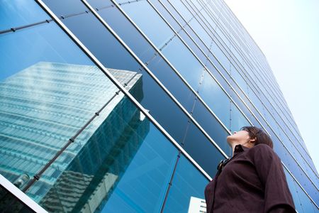 successful businesswoman looking up next to her office buildingの写真素材