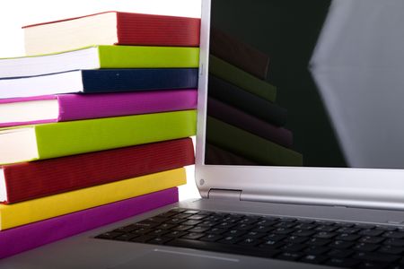 Colorful books next to a modern laptopの写真素材