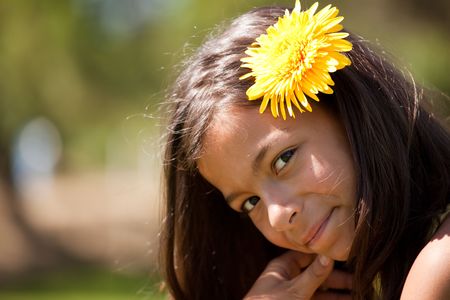 young beautiful child with a yellow flower on her headの写真素材