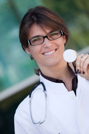 Friendly female doctor smiling to you next to a clinicの写真素材