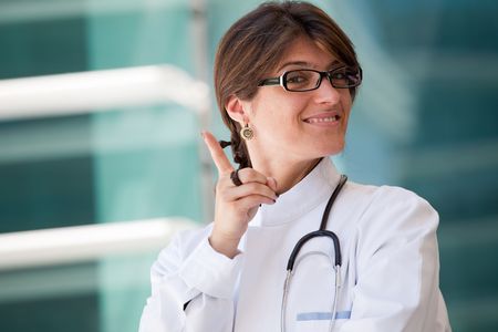 Friendly female doctor smiling to you next to a clinicの写真素材