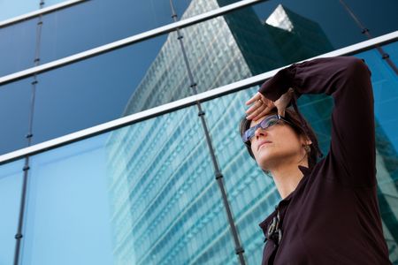 businesswoman looking away next to her office buildingの写真素材