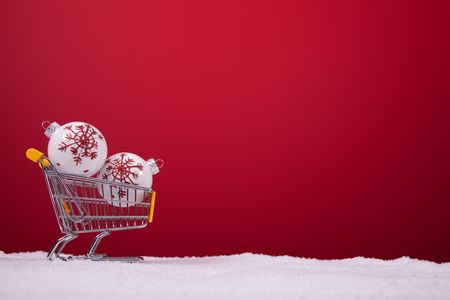 christmas balls in a shopping cart over a red backgroundの写真素材