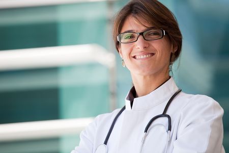 Friendly female doctor smiling to you next to a clinicの写真素材