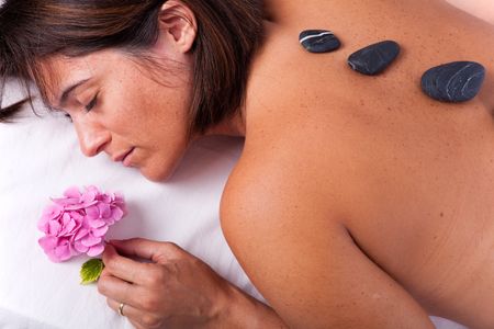 young beautiful woman in a spa enjoying a hot stone treatmentの写真素材
