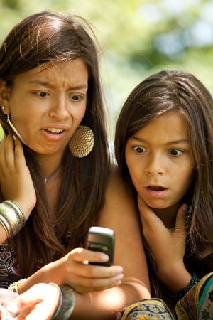 two young sisters reading a new sms at the cellularの写真素材