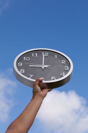 hand holding a wall clock up to the skyの写真素材