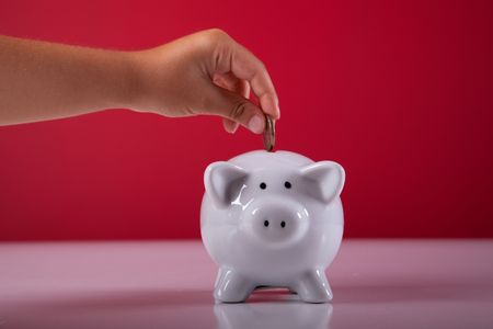 hand of a child saving some money on his piggybankの写真素材