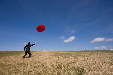 businessman chasing his insurance solution (an umbrella)の写真素材