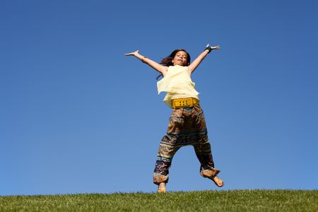 young female child jumping on the grassの写真素材
