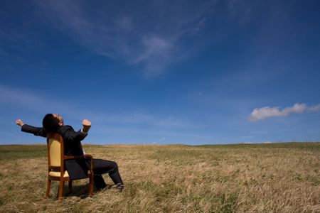 businessman sitting in a chair in outdoor looking to the fieldの写真素材