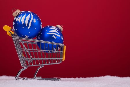 christmas balls in a shopping cart over a red backgroundの写真素材