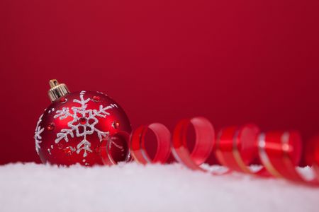 christmas colorful balls over the snow with a red background (selective focus)の写真素材