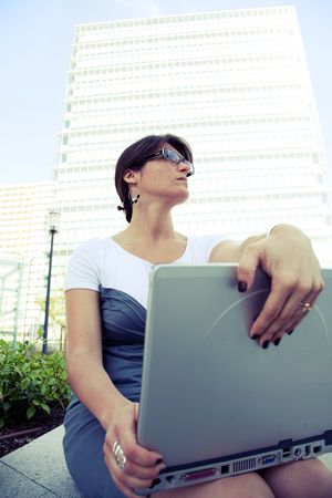 young businesswoman working with her laptop outdoor (cross processed image)の写真素材